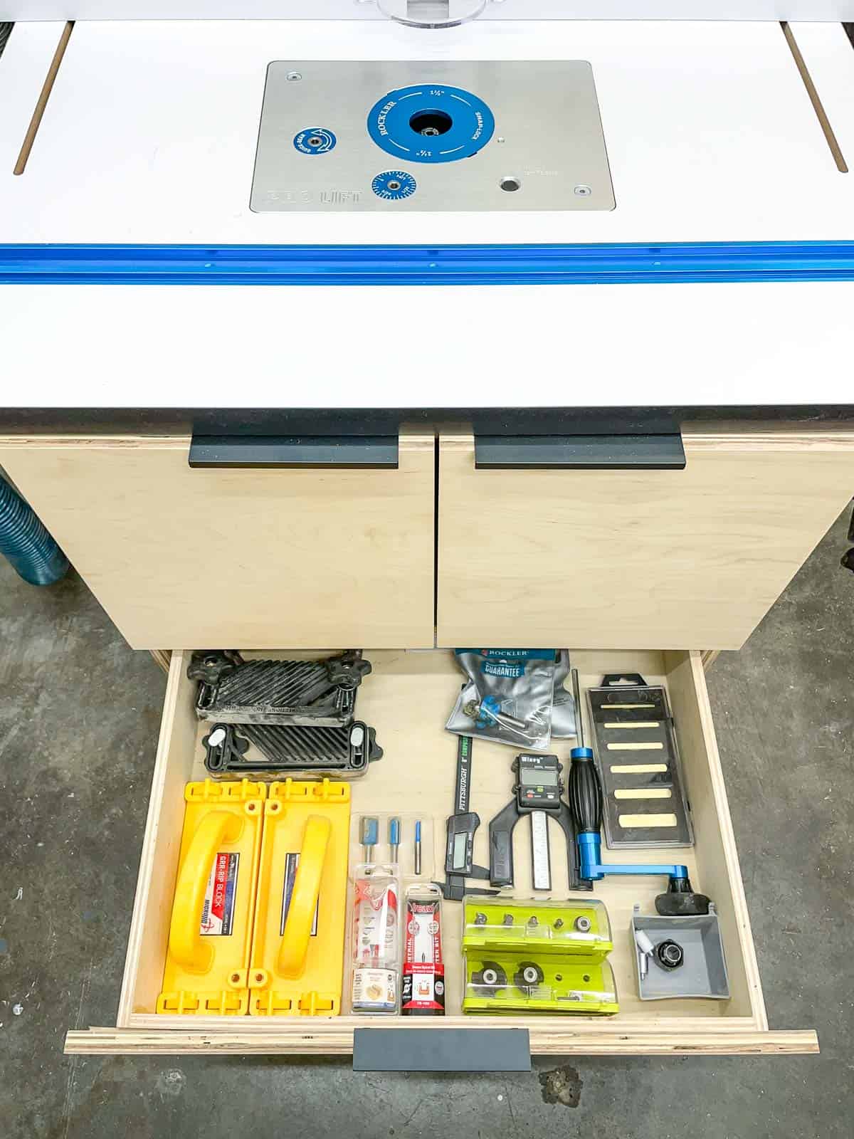 DIY router table with drawer pulled out to reveal routing tools and bits