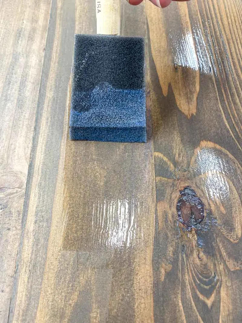 applying polycrylic to the rustic wood surface with a foam brush
